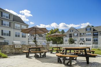 an outdoor patio with picnic tables and umbrellas in front of an apartment building